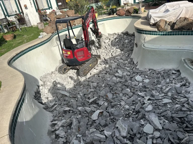 Excavator demolishing concrete pool during demolition project in Sacramento.
