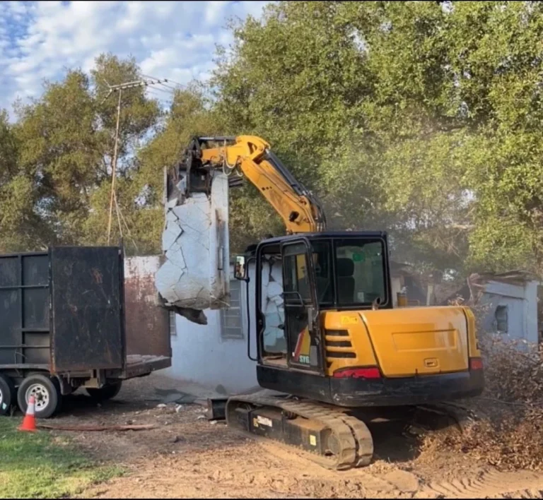 Empire Demolition & Hauling excavator demolishing concrete structure and loading debris into trailer.