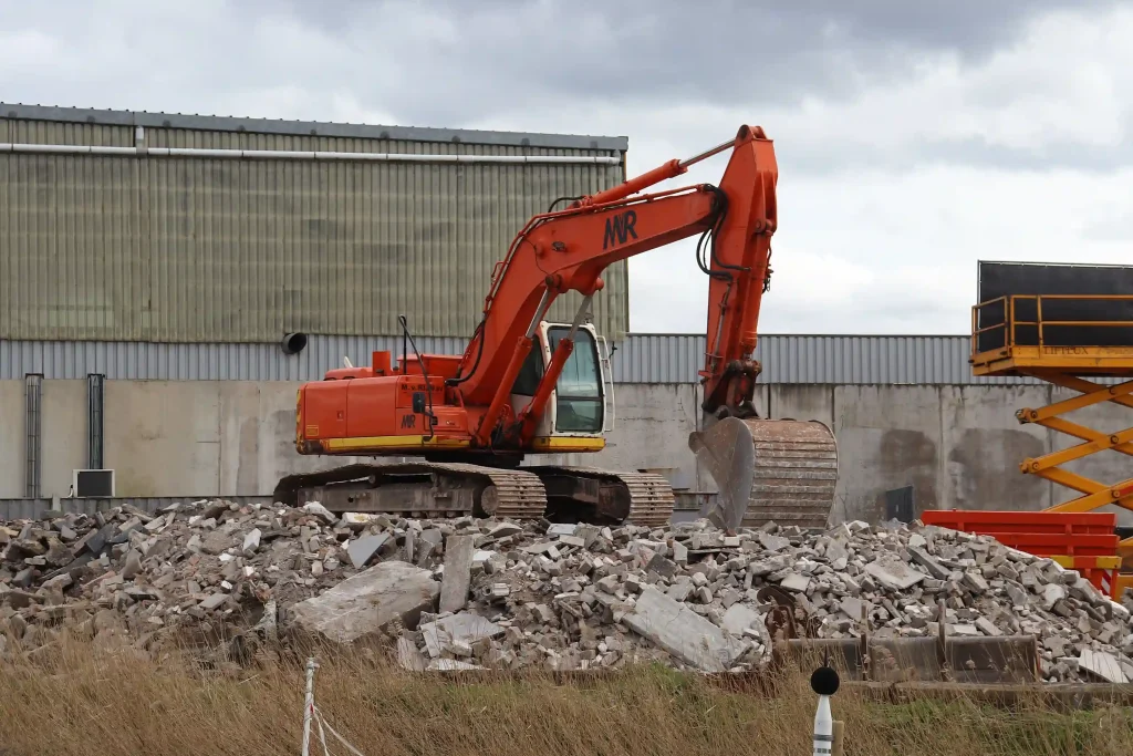 Orange excavator demolishing a commercial building for a demolition contractor in North Highlands, CA