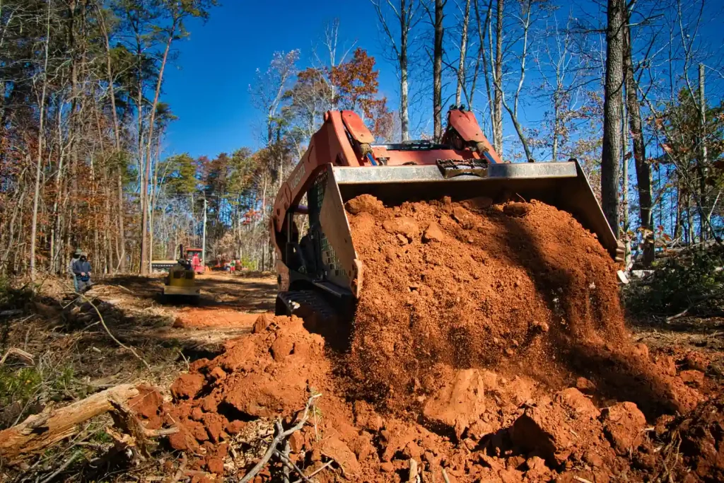 Excavator bucket full of red soil during foundation digging for an excavating contractor in Foothill Farms, CA