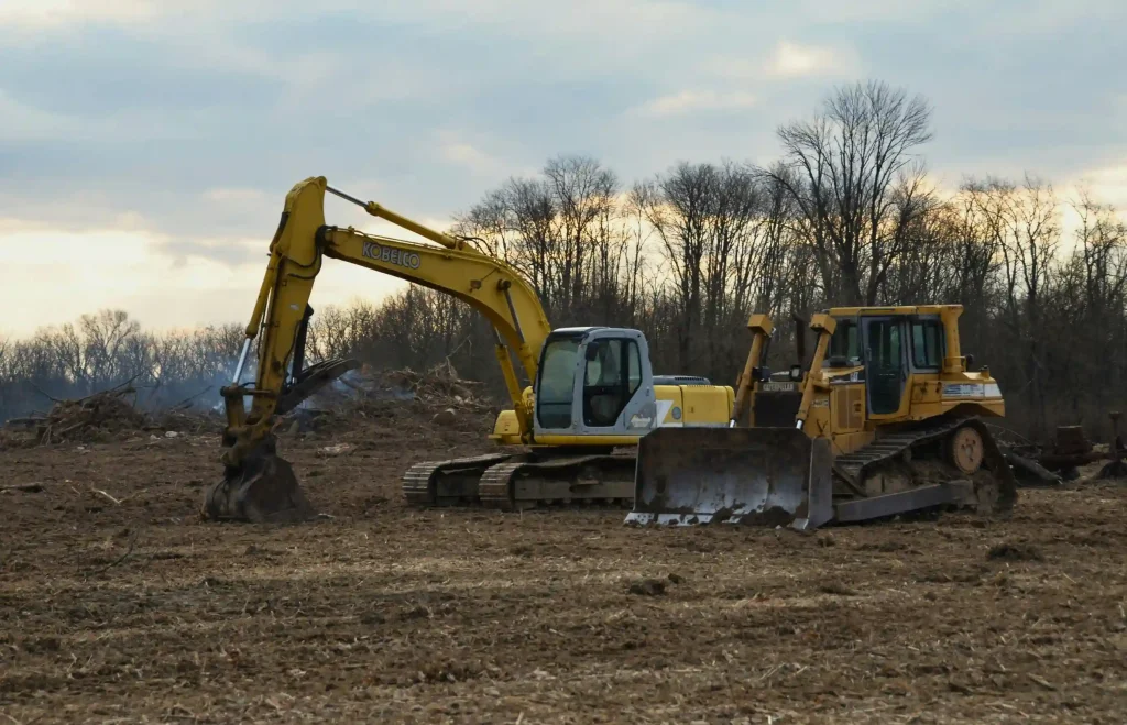 Excavator and dozer clearing overgrown land at dusk for land clearing in Granite Bay, CA